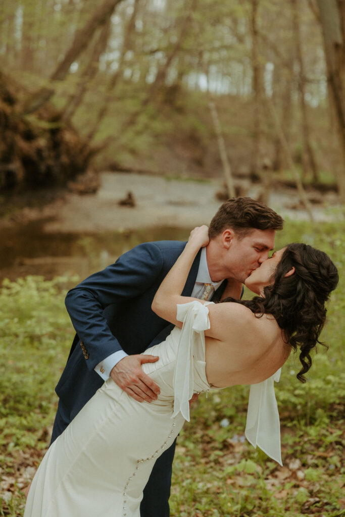 A man dipping his bride for a kiss in the woods 