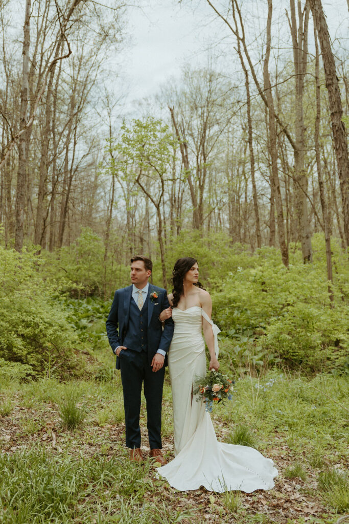 A bride and groom standing together in the woods at The Brook