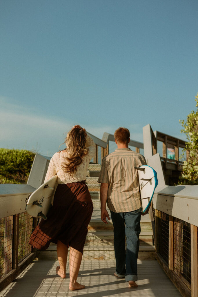 man and woman walking to St Augustine beach carrying surf boards