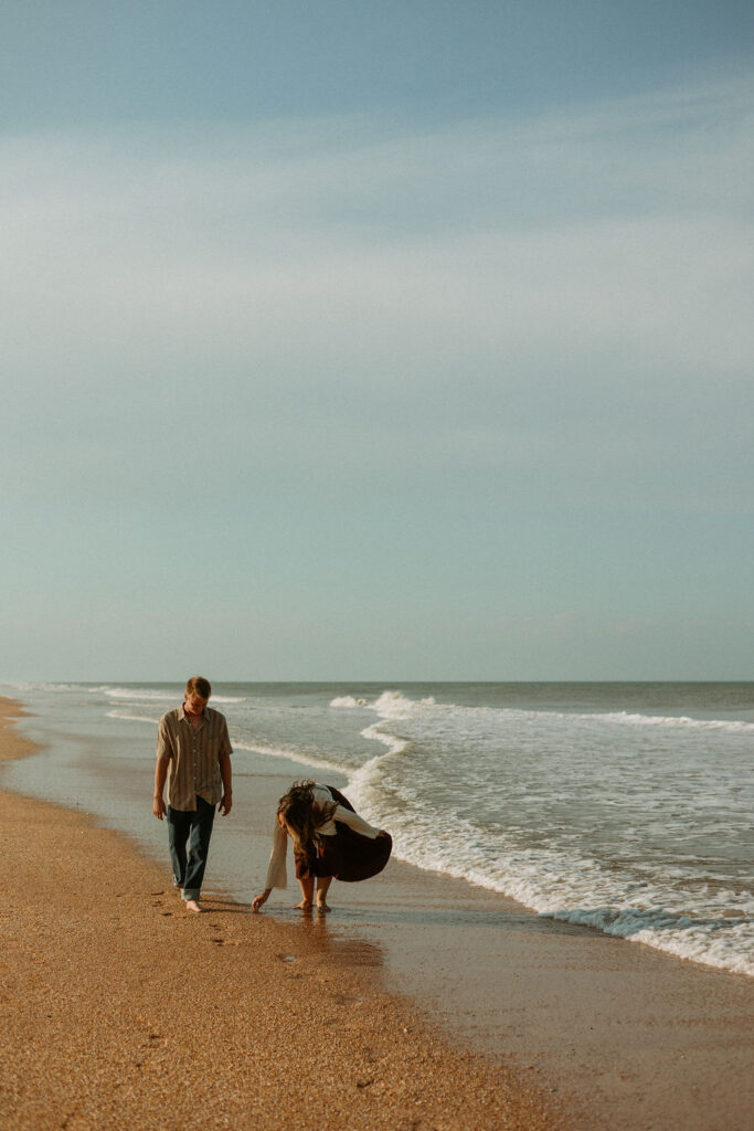 a couple walking along the St Augustine beach picking up sea shells