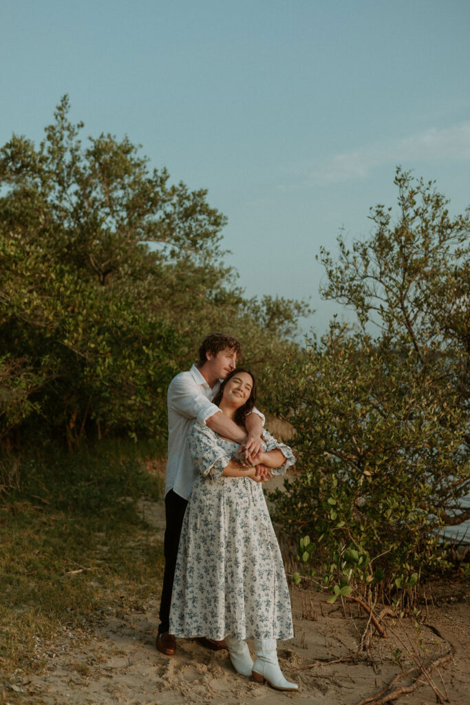 man embracing woman in a hug by the beach