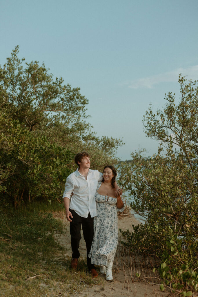 couple strolling down a path by the beach