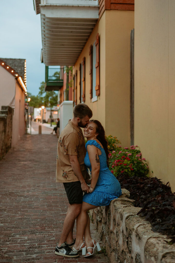 man kissing woman's forehead while sitting near a road