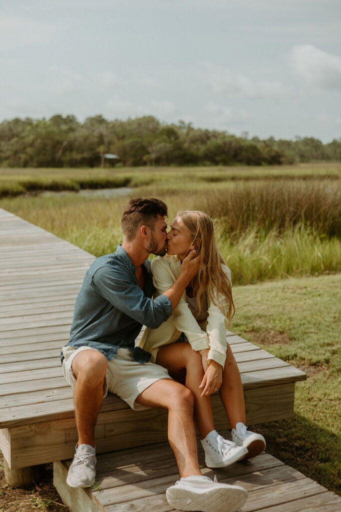 couple sitting and kissing on a pier 