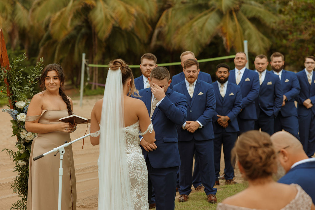 groom covering his face from crying while his bride reads her vows 