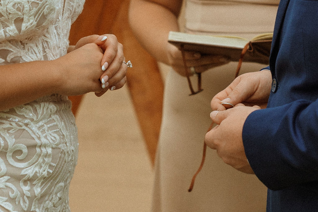 closeup of groom holding brides wedding band 