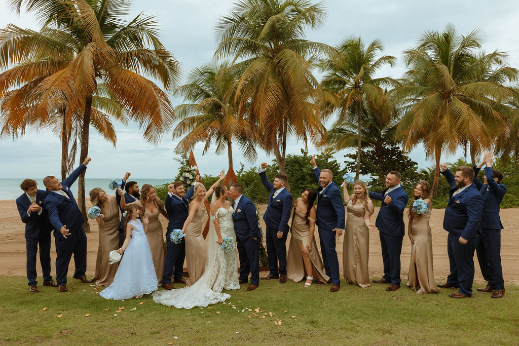 full wedding party photo with bridesmaids and groomsmen cheering for the couple