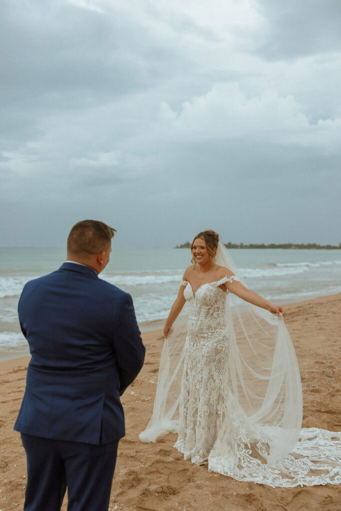 groom watching bride twirl her dress around in the sand