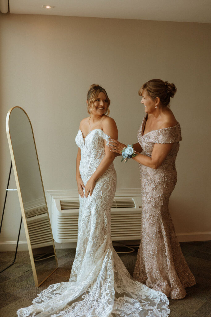 mother of the bride helping the bride get dressed