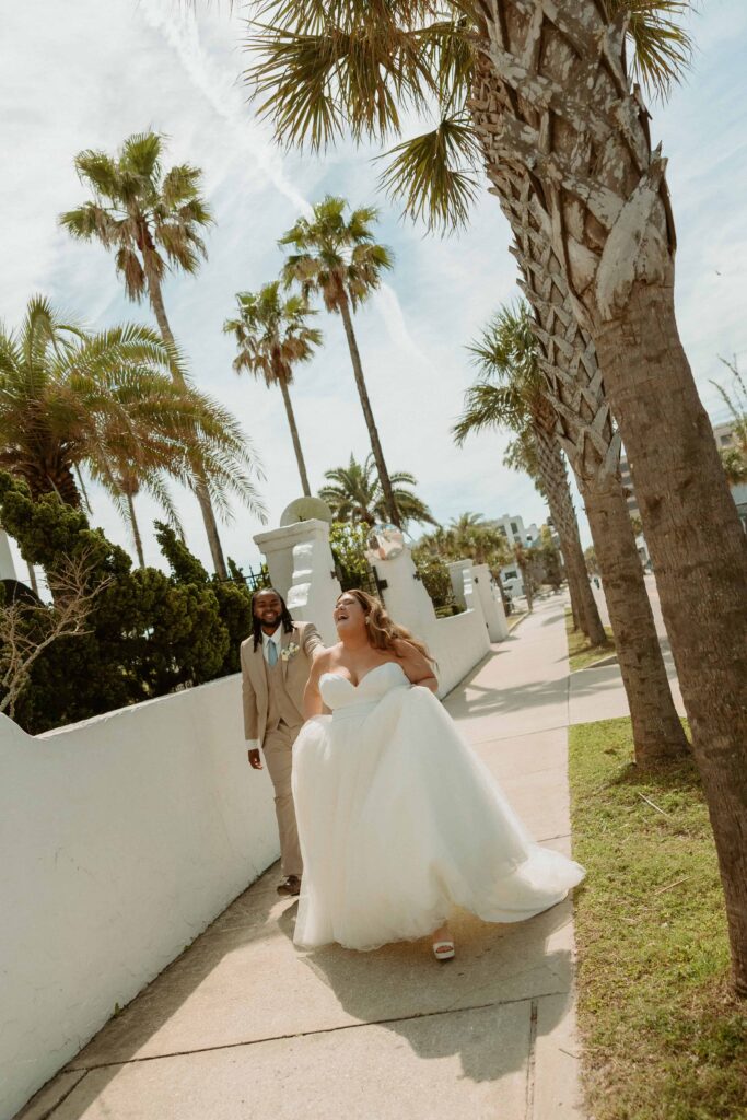 bride laughing while walking down the street with her groom to elope