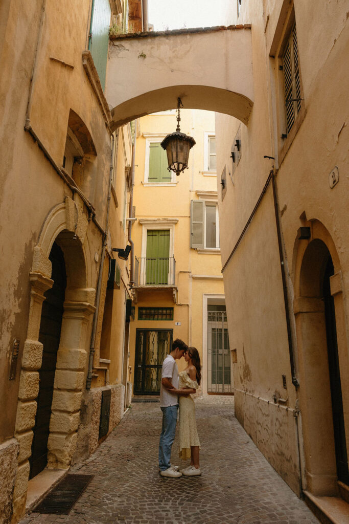 Couple standing under a lantern on the cobble street of Verona 