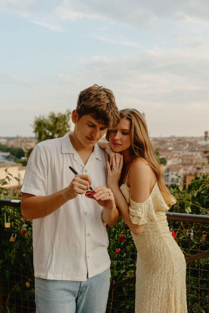 Man writing on a locket in Verona, Italy for their engagement session
