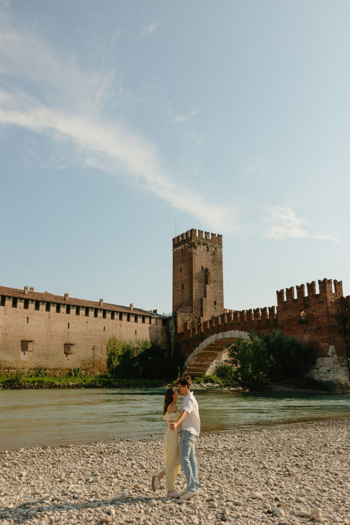 Historic Verona bridge with couple dancing on the rocks