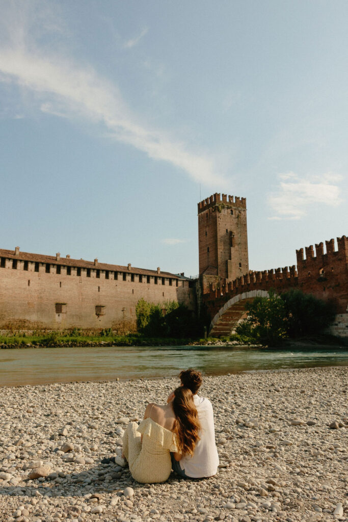 Couple sitting by the bridge for their Verona Italy engagement session