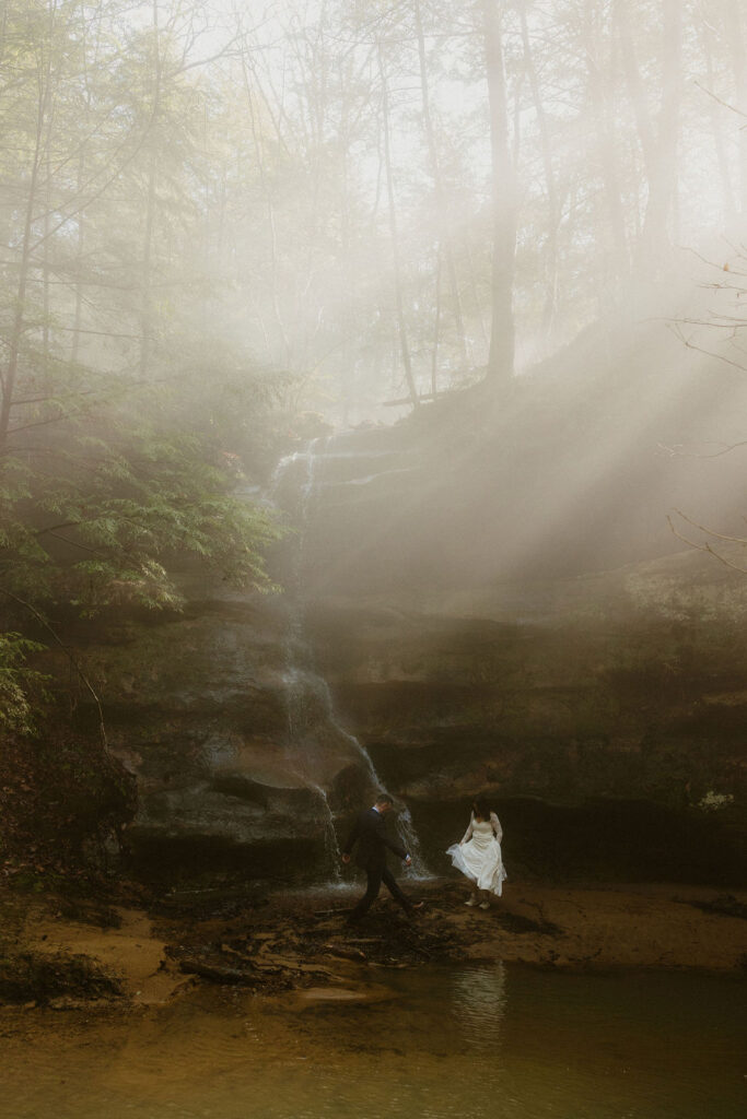 Bride and groom surrounded by mist at a waterfall in Hocking Hills during their elopement