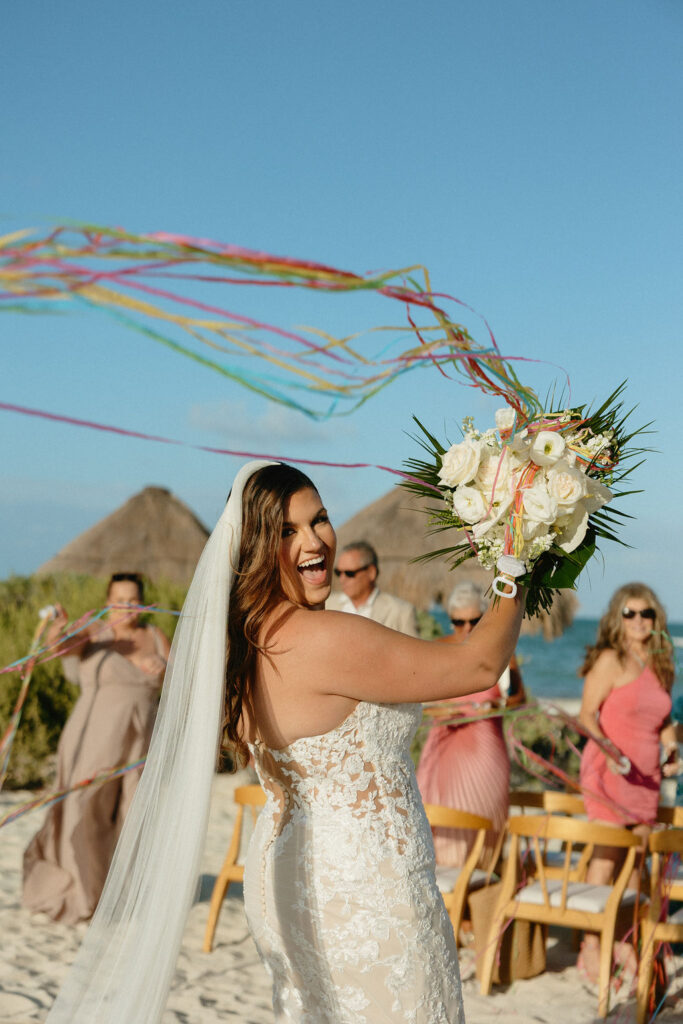 Bride cheering with streamers in her bouquet after her Secrets Playa Blanca ceremony