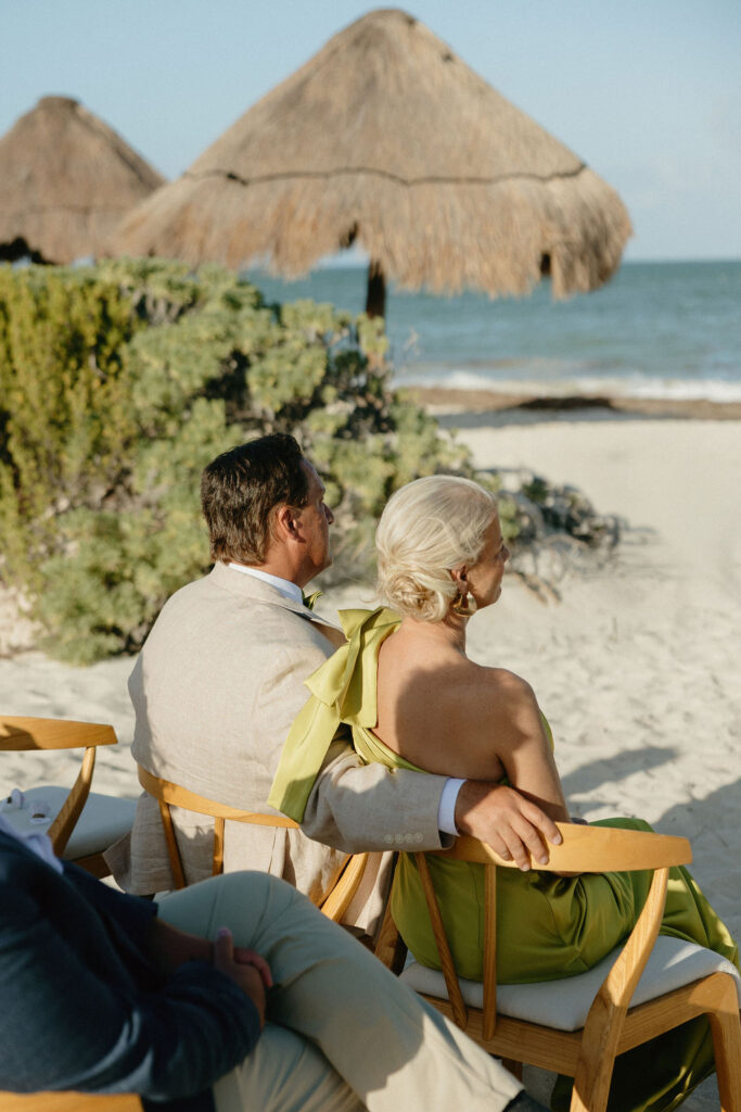 Brides parents sitting together for their daughters wedding in Secrets Playa Blanca 