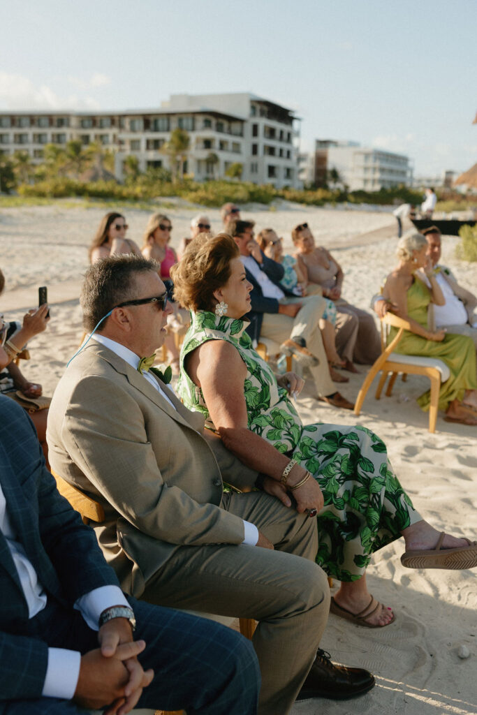Family watching a couple get married on the beach at Secrets Playa Blanca 