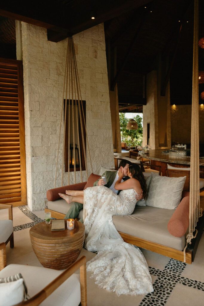 Bride and groom kissing on a couch at Secrets Playa Blancas resort bar